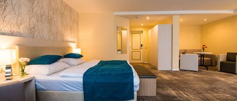 Ein Hotelzimmer mit Bett, Nachttischen, einem Schreibtisch und einem Sessel.