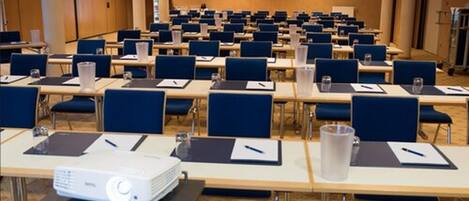A conference room with rows of tables, chairs, and a projector.