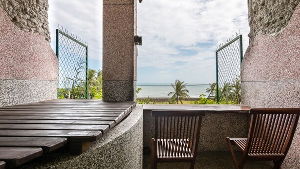 A terrace with a view of the ocean, featuring a wooden bench, two wooden chairs, and a stone wall. - Pasa Beach Resort (Beinan)