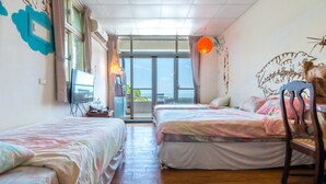 A hotel room with two beds, a television, a desk, and a view of the sea. - Pasa Beach Resort (Beinan)