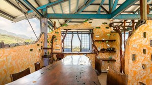 A rustic dining area with a long wooden table, rustic decor, and a view of the outdoors. - Pasa Beach Resort (Beinan)