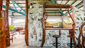A rustic outdoor seating area with wooden furniture and a stone wall adorned with green bottles. - Pasa Beach Resort (Beinan)