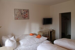 A room with two beds, a desk, a chair, a flat-screen TV, and a door leading to a closet. - Hotel Schwartze (Weimar)