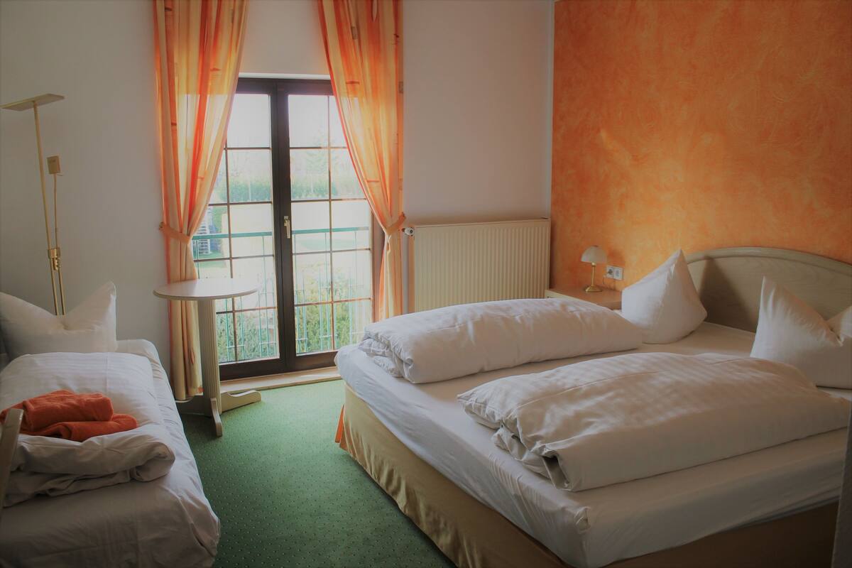 Une chambre d’hôtel avec deux lits, une fenêtre avec des rideaux, un radiateur et une lampe sur une table de chevet.