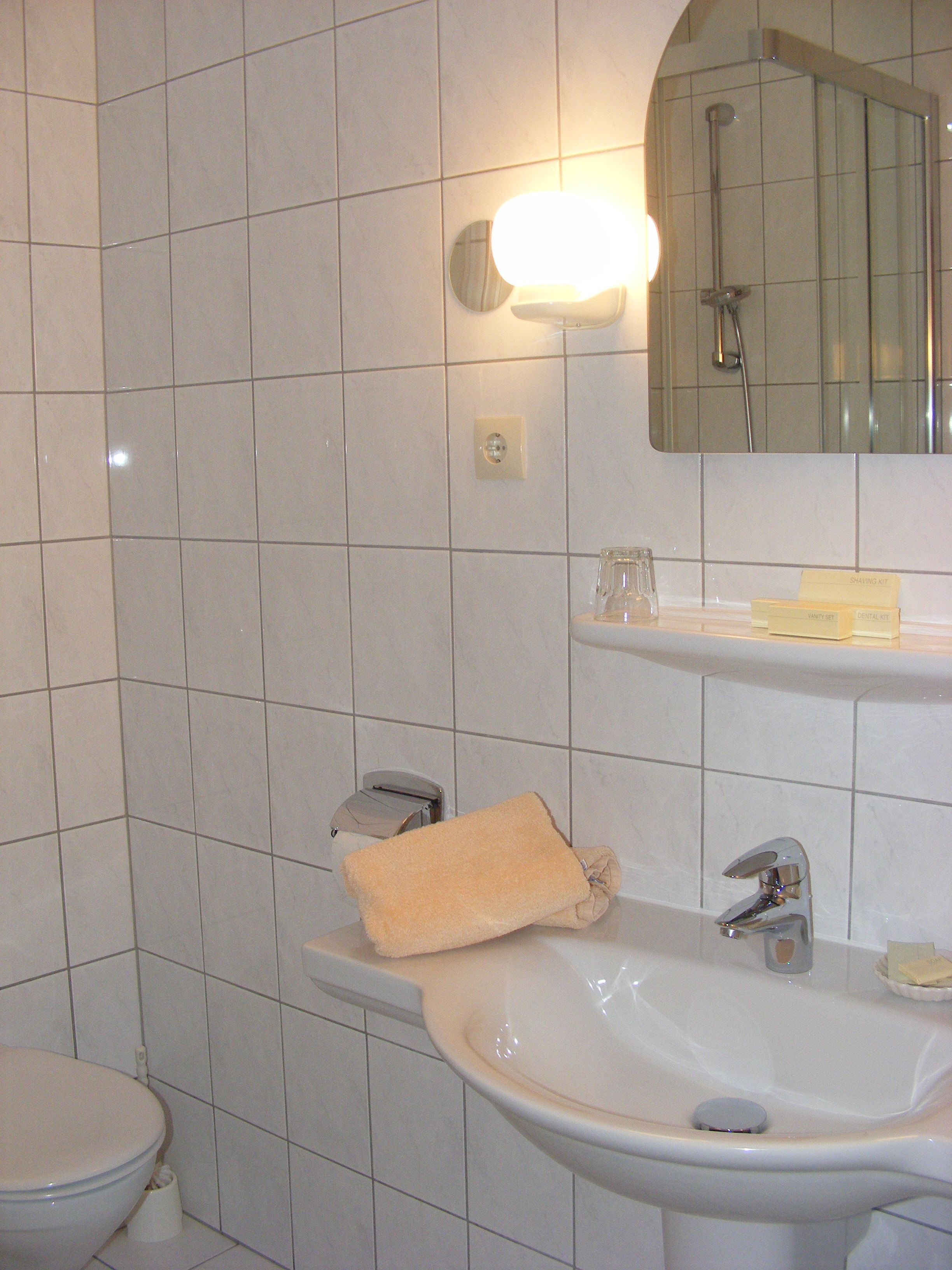 A bathroom with a toilet, sink, and mirror.