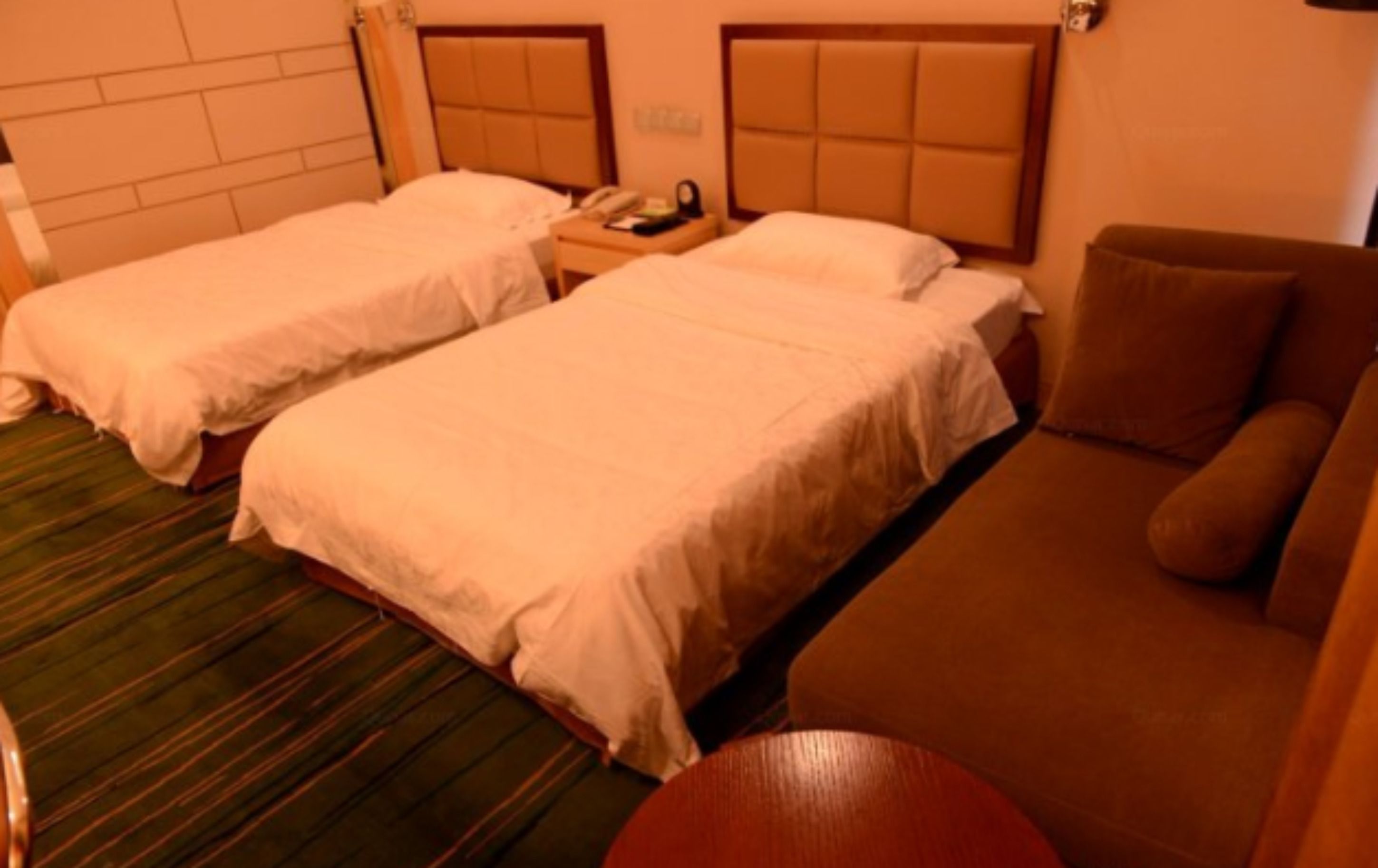 Ett hotellrum med två separata sängar, en soffa och ett litet bord.