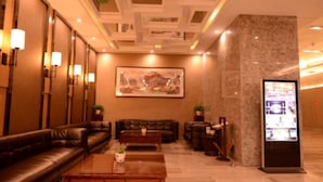 A lobby with leather sofas, a coffee table, a reception desk, and a large painting on the wall.