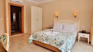 A bedroom with a bed, nightstands, a wardrobe, and an air conditioning unit. - The Blue Lagoon Deluxe Hotel (Fethiye)
