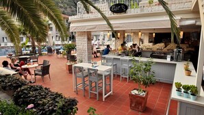 An outdoor dining area with tables and chairs, a bar counter, and potted plants. - The Blue Lagoon Deluxe Hotel (Fethiye)