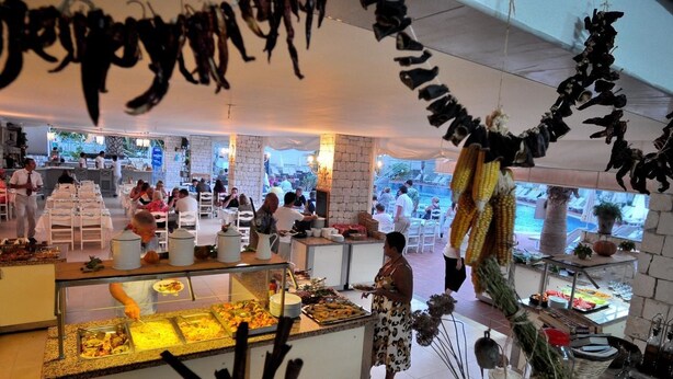 A buffet area with various food options, a bar, and a seating area with tables and chairs. - The Blue Lagoon Deluxe Hotel (Fethiye)
