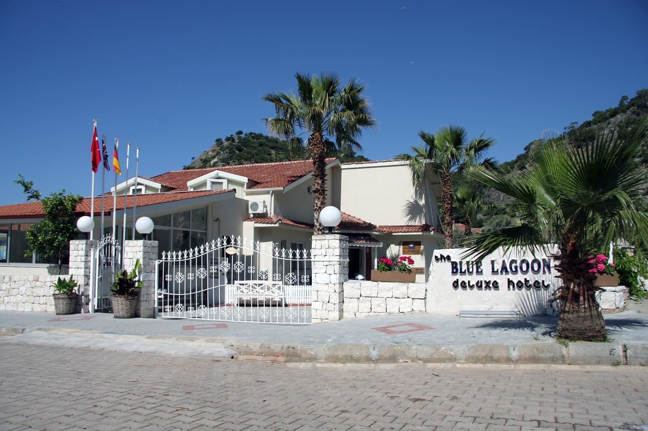 A hotel with a stone facade, a gated entrance, and a sign that reads "Blue Lagoon deluxe hotel".