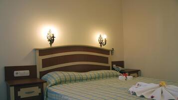 Una habitación de hotel con cama, mesitas de noche y lámparas de pared.