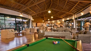 A pool table in a spacious room with comfortable seating and large windows.