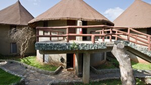 A traditional building with a conical roof, a stone pathway, and a wooden bridge.