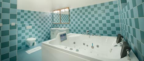 A bathroom with a bathtub, two sinks, a toilet, and a mirror.