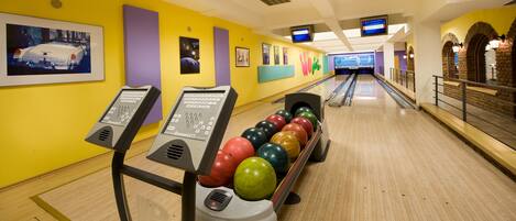 A bowling alley with multiple lanes, bowling balls, and a bowling ball return system.