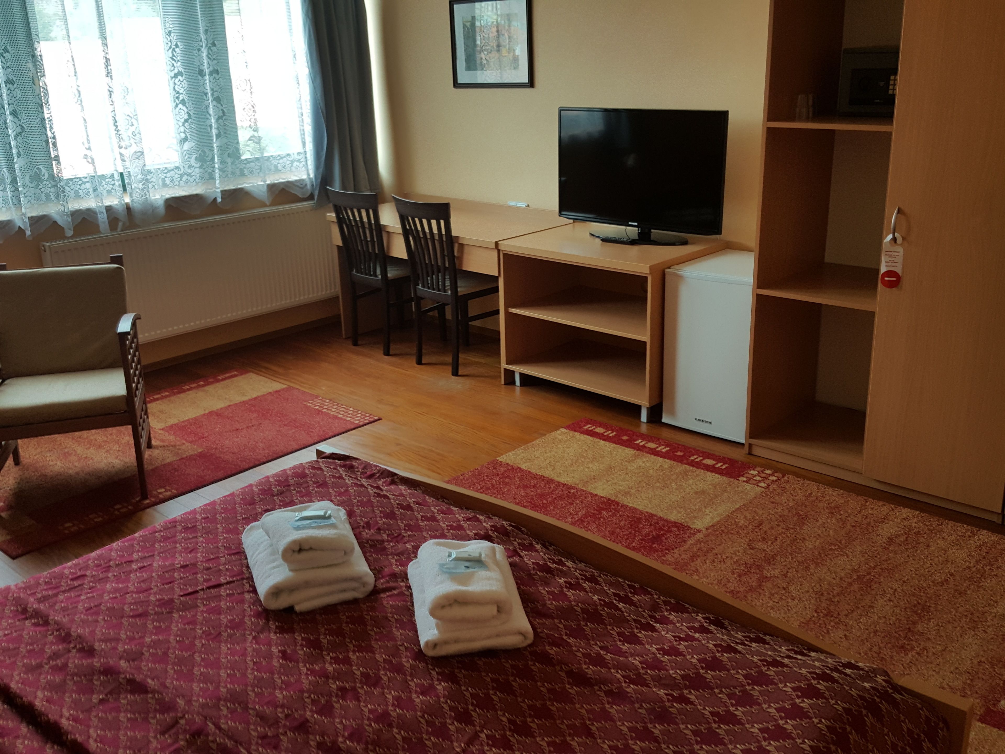 Ett hotellrum med en säng, ett skrivbord med en tv, en stol och en garderob.