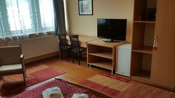 Ett hotellrum med en säng, ett skrivbord med en tv, en stol och en garderob.