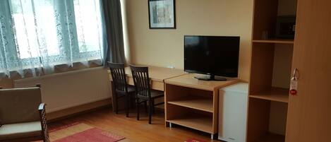 Una habitación de hotel con cama, escritorio con televisor, silla y armario.