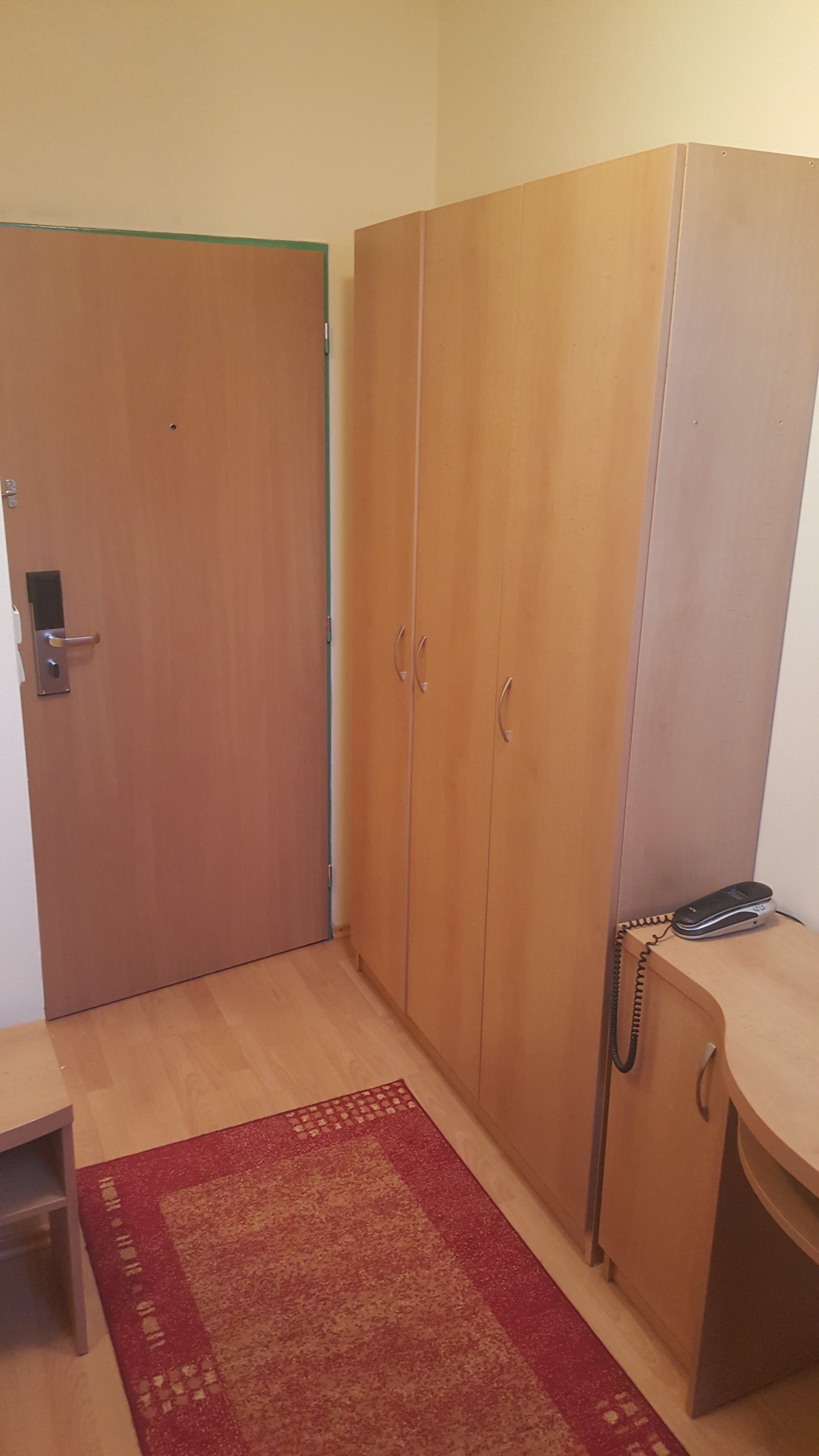 Une pièce comprenant une armoire en bois, un bureau et un téléphone.