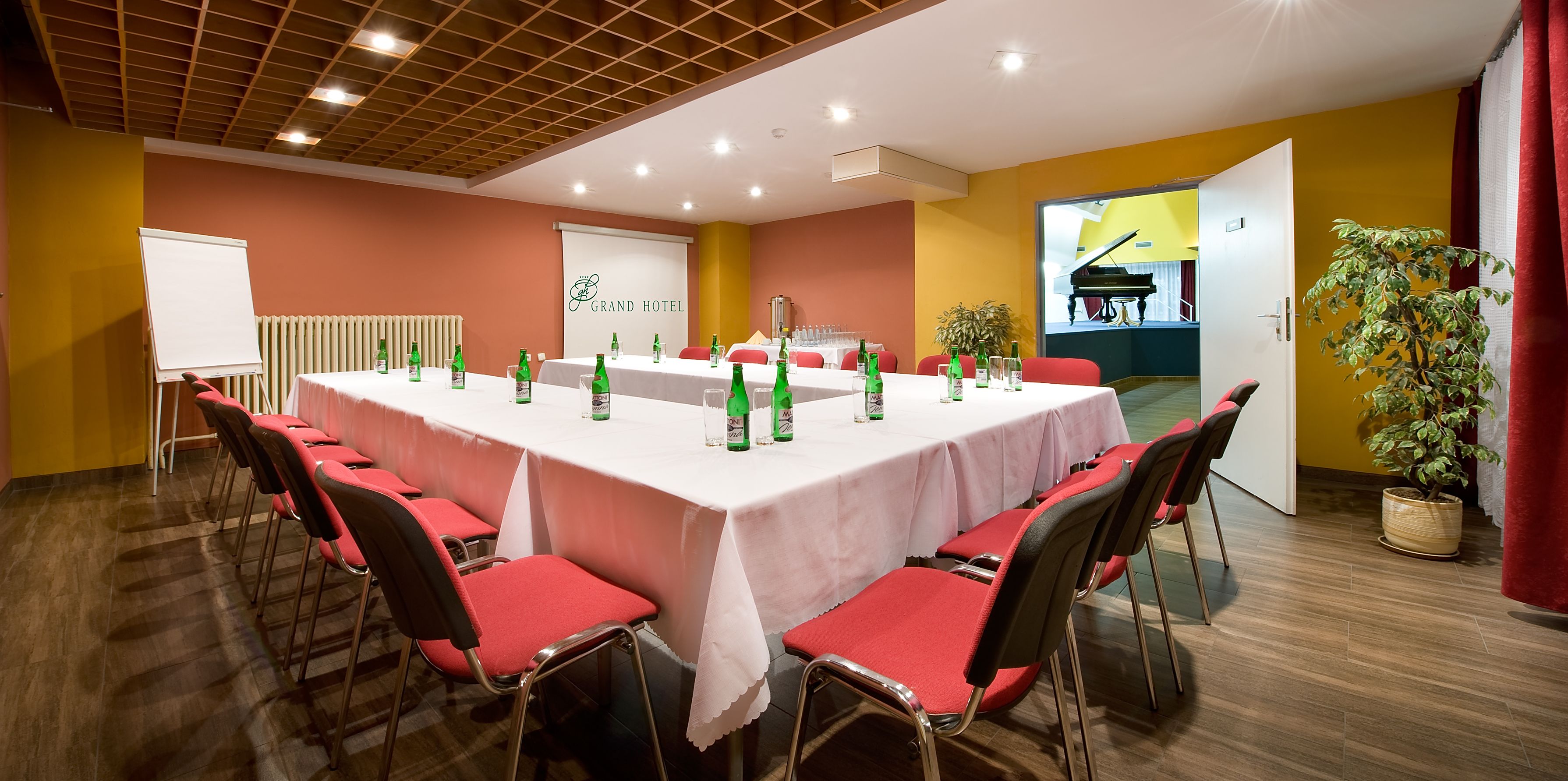 A conference room with a long table, red chairs, and green bottles.