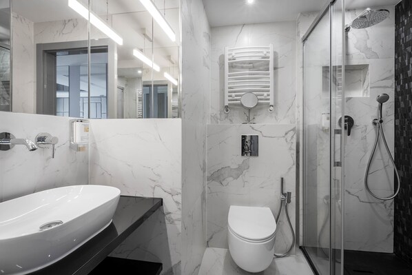 A modern bathroom with a white sink, toilet, and glass-enclosed shower.