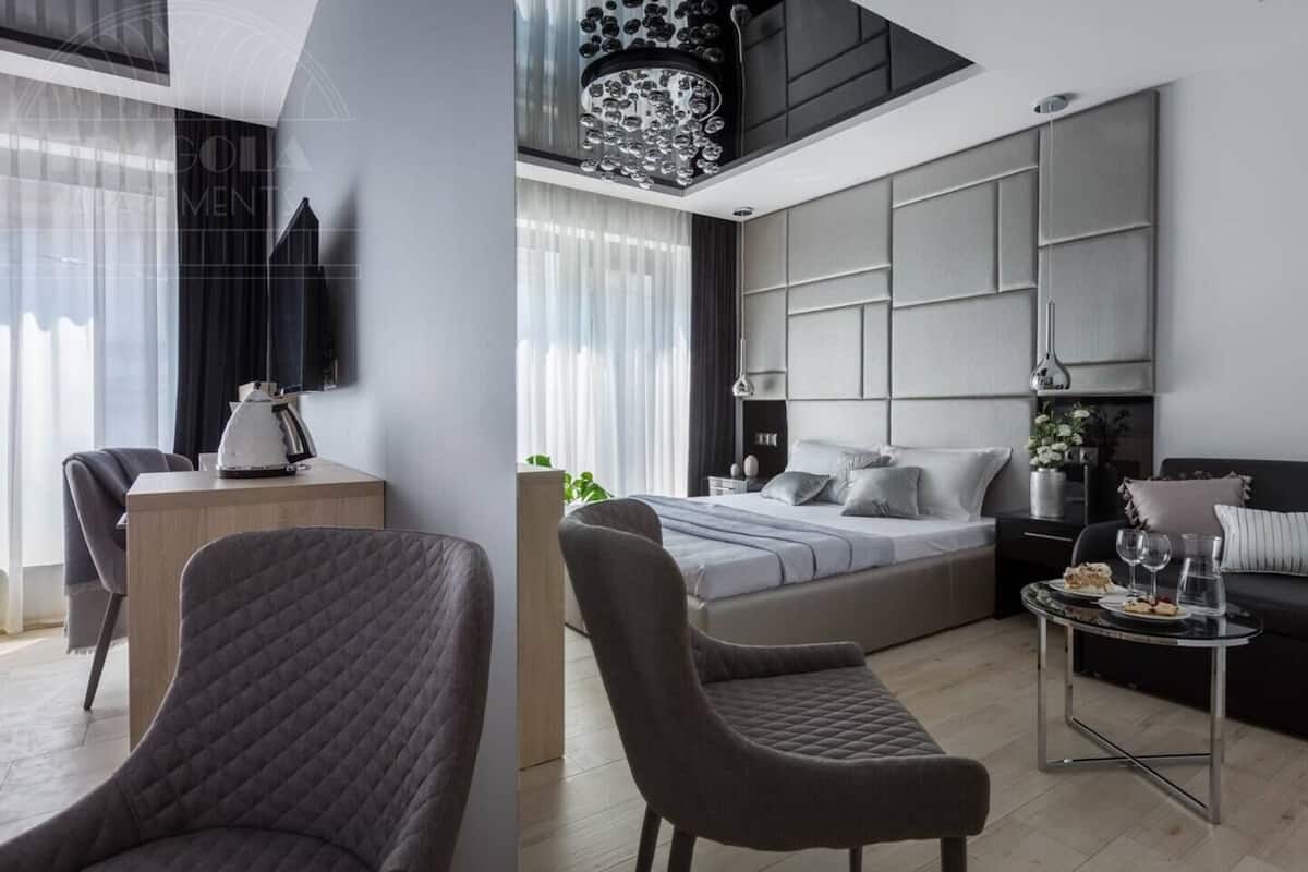 Un dormitorio moderno con cama, mesitas de noche, escritorio y zona de estar.