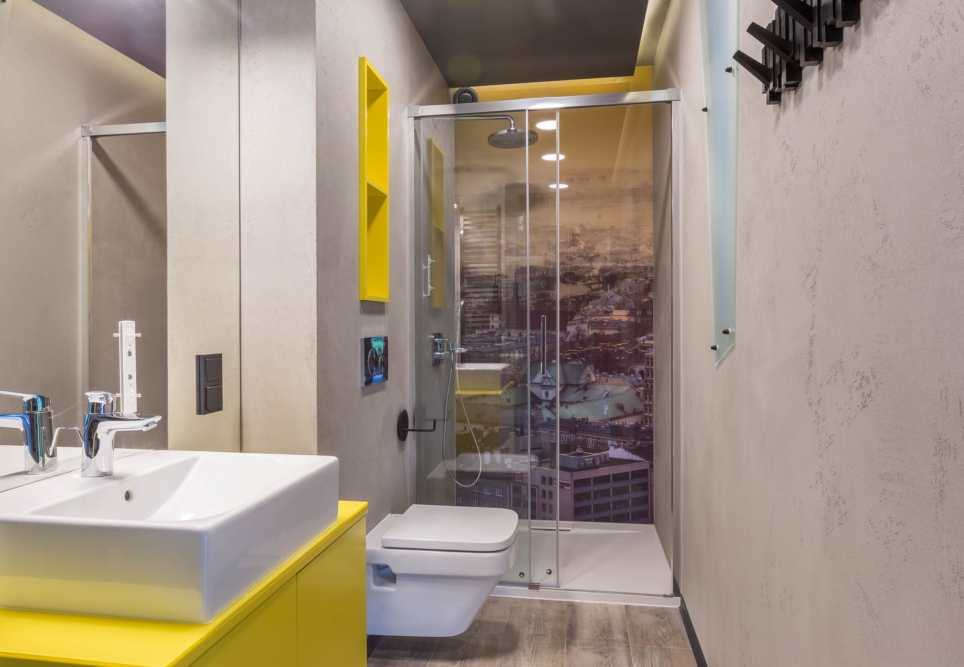 A modern bathroom with a glass-enclosed shower, a white sink, and a yellow vanity.