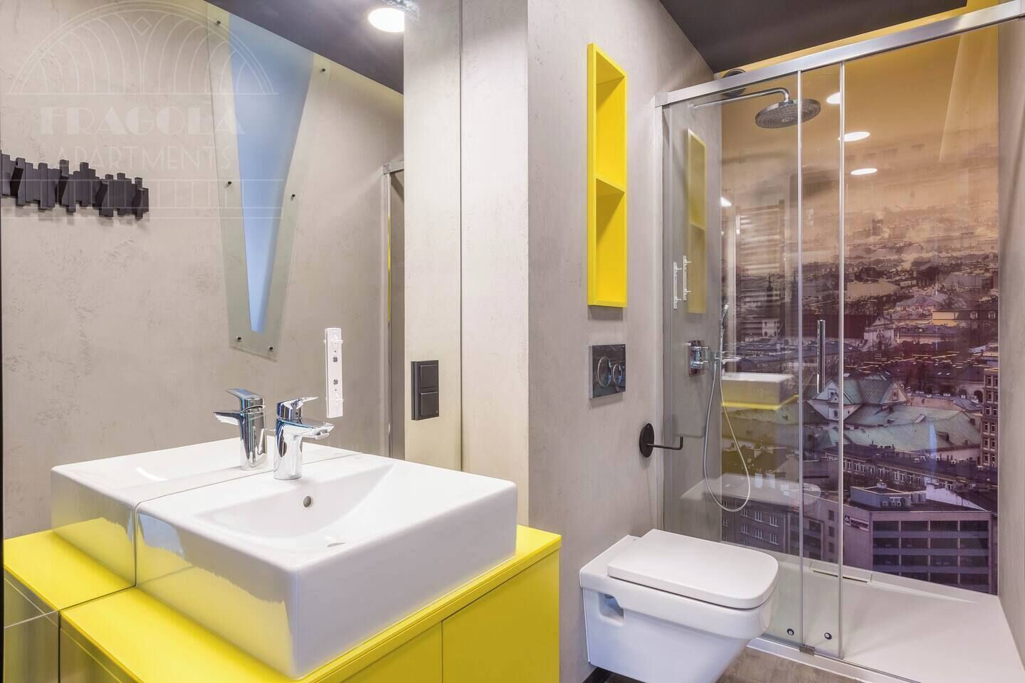 A modern bathroom with a white sink, yellow vanity, and a glass shower enclosure with a cityscape view.
