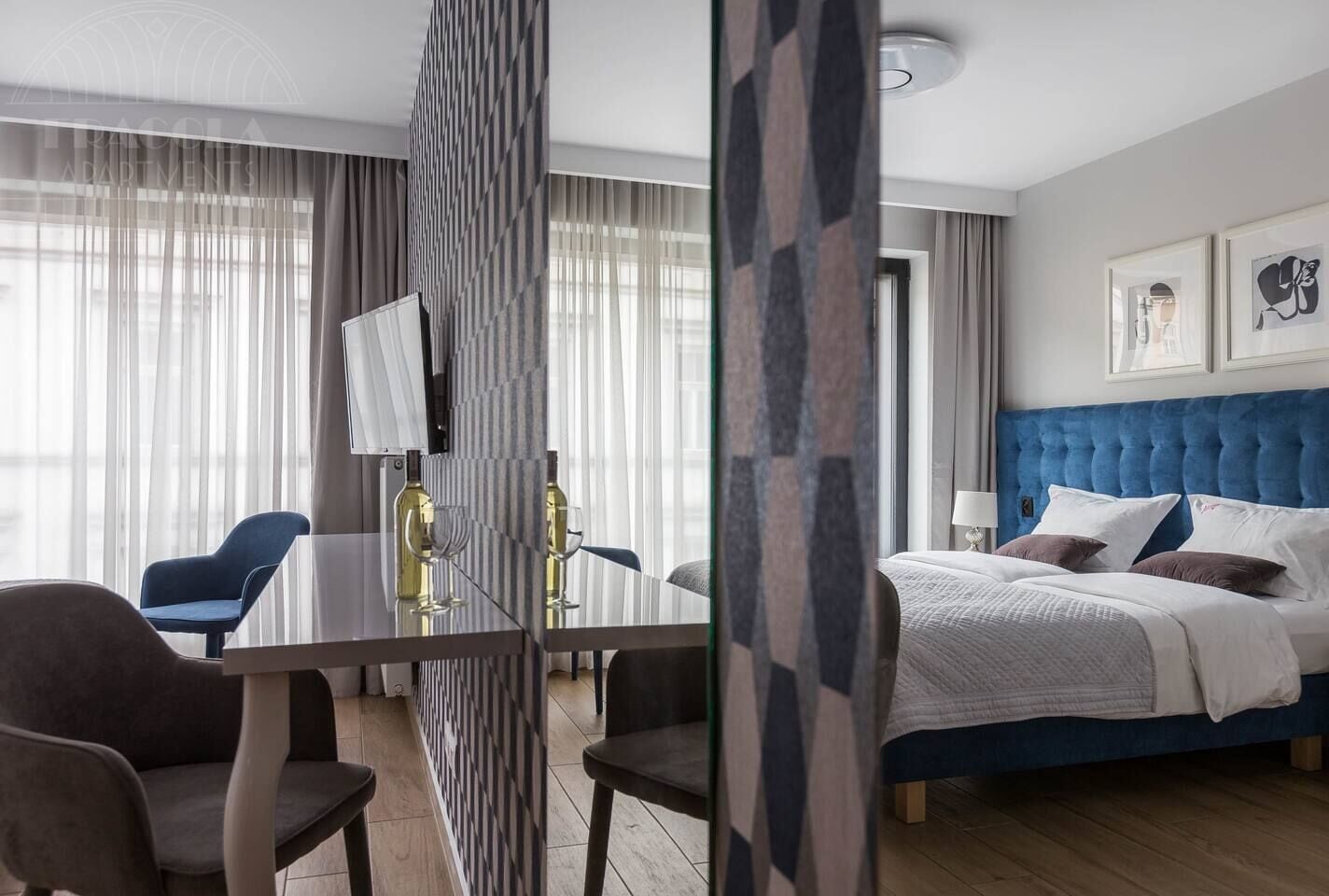 A hotel room with a bed, a desk, a chair, and a large window with curtains.