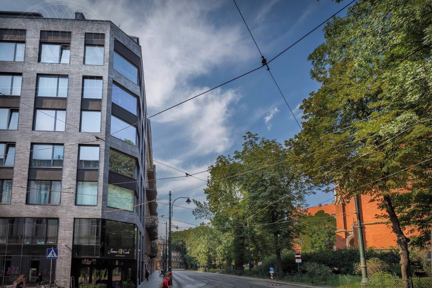 A modern building with multiple floors, large windows, and a pedestrian crossing sign.