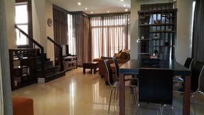 A modern living room with a dining area, a staircase, and a bookshelf. - Teddy Bear Villa Hua Hin 2 (Cha-am)