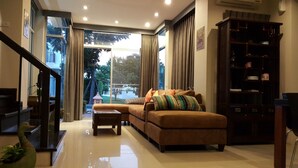 A modern living room with a sectional sofa, a coffee table, and a bookshelf. - Teddy Bear Villa Hua Hin 2 (Cha-am)