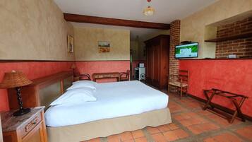 Quarto de hotel com cama, mobiliário de madeira, televisão e parede de tijolos.