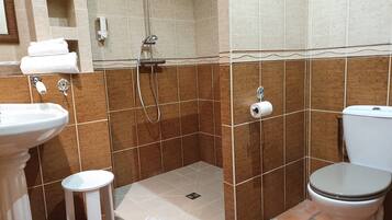 Une salle de bain comprenant un lavabo, des toilettes et un espace douche.