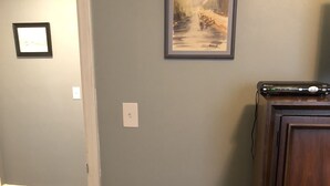 Ein Zimmer mit einem Holzschrank, einem gerahmten Gemälde an der Wand und einem kleinen Tisch mit gefalteten Handtüchern.