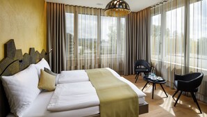 Une chambre d’hôtel avec un grand lit, une petite table avec une chaise et une vue à travers les rideaux.