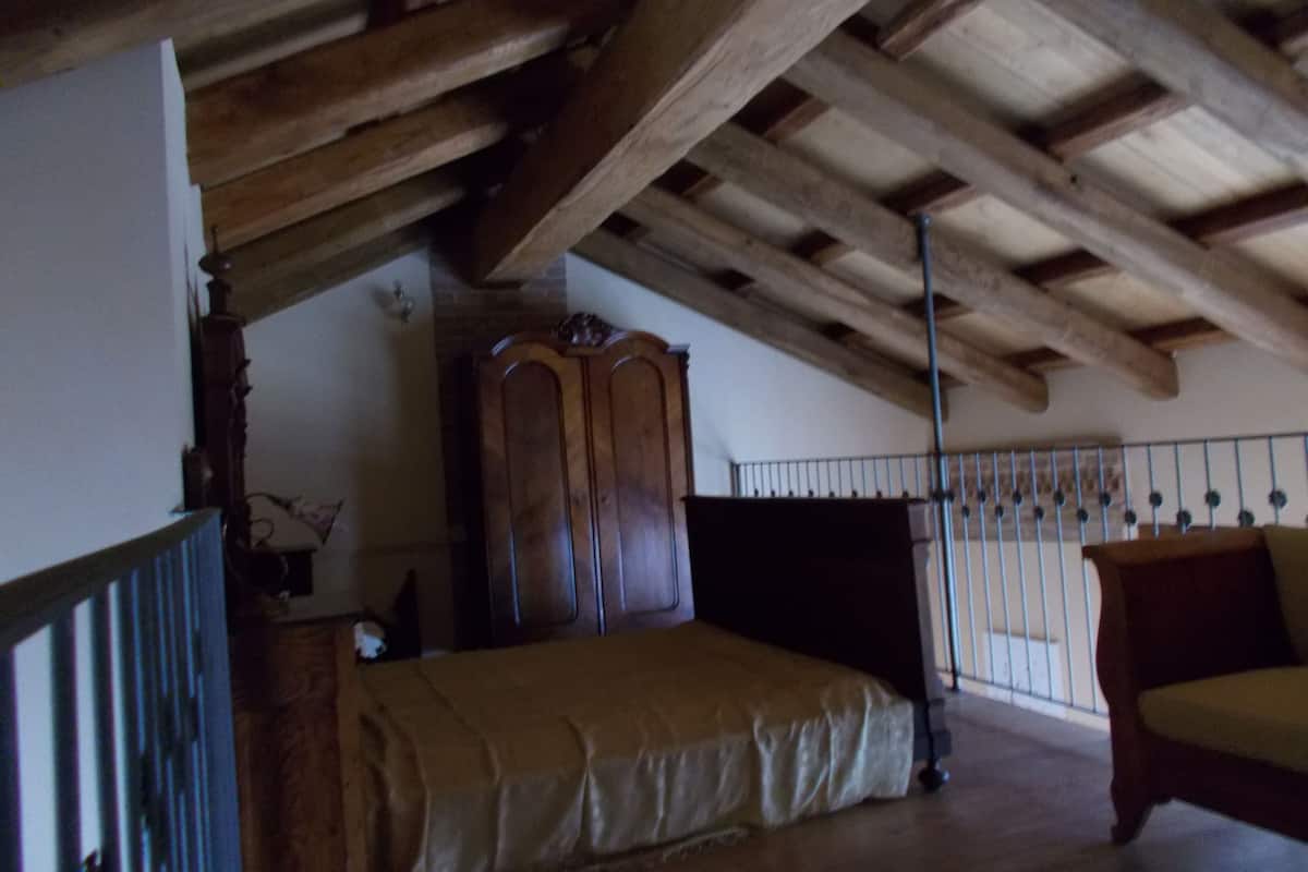 Une pièce avec un plafond en bois, un lit, une armoire et une chaise.