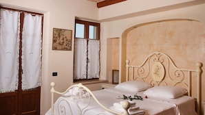A bedroom with a bed, curtains, a painting, and a window.