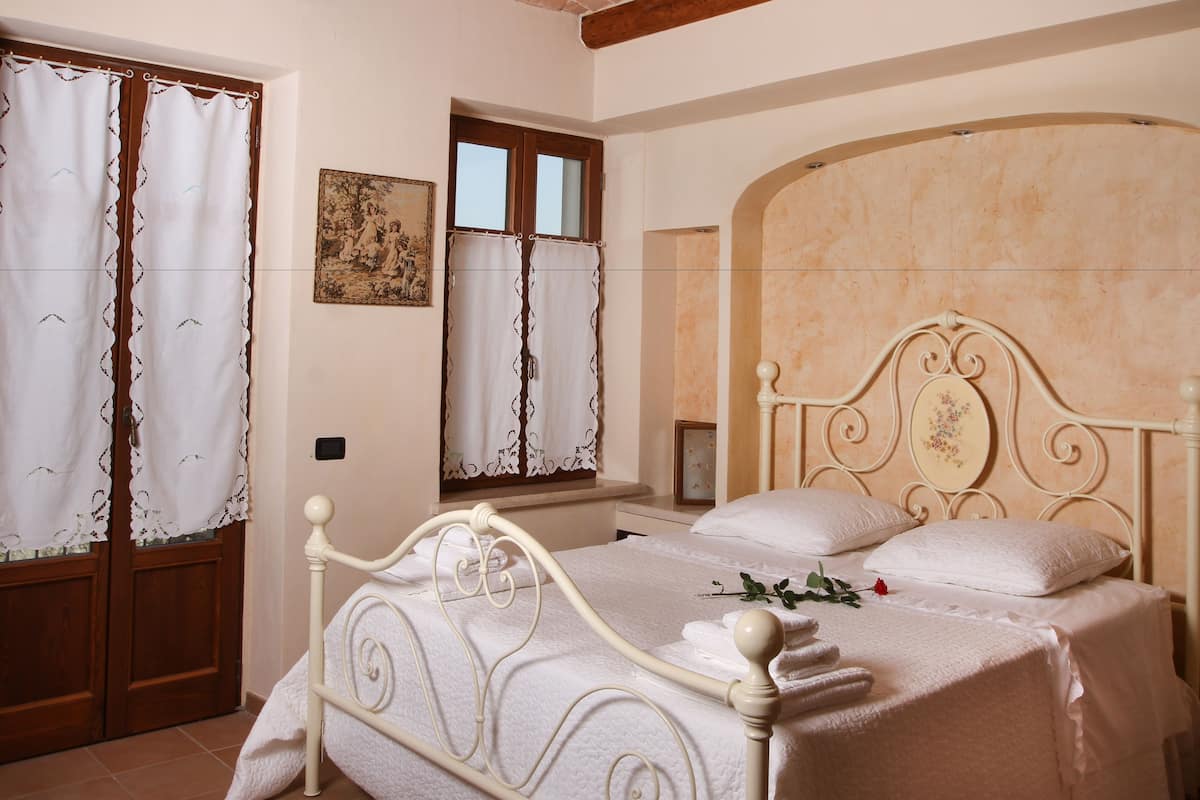 Une chambre à coucher avec un lit, des rideaux, un tableau et une fenêtre.