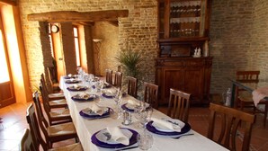 A long dining table set for a meal in a rustic room with stone walls and wooden furniture.