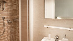 Un baño moderno con ducha, lavamanos y espejo.