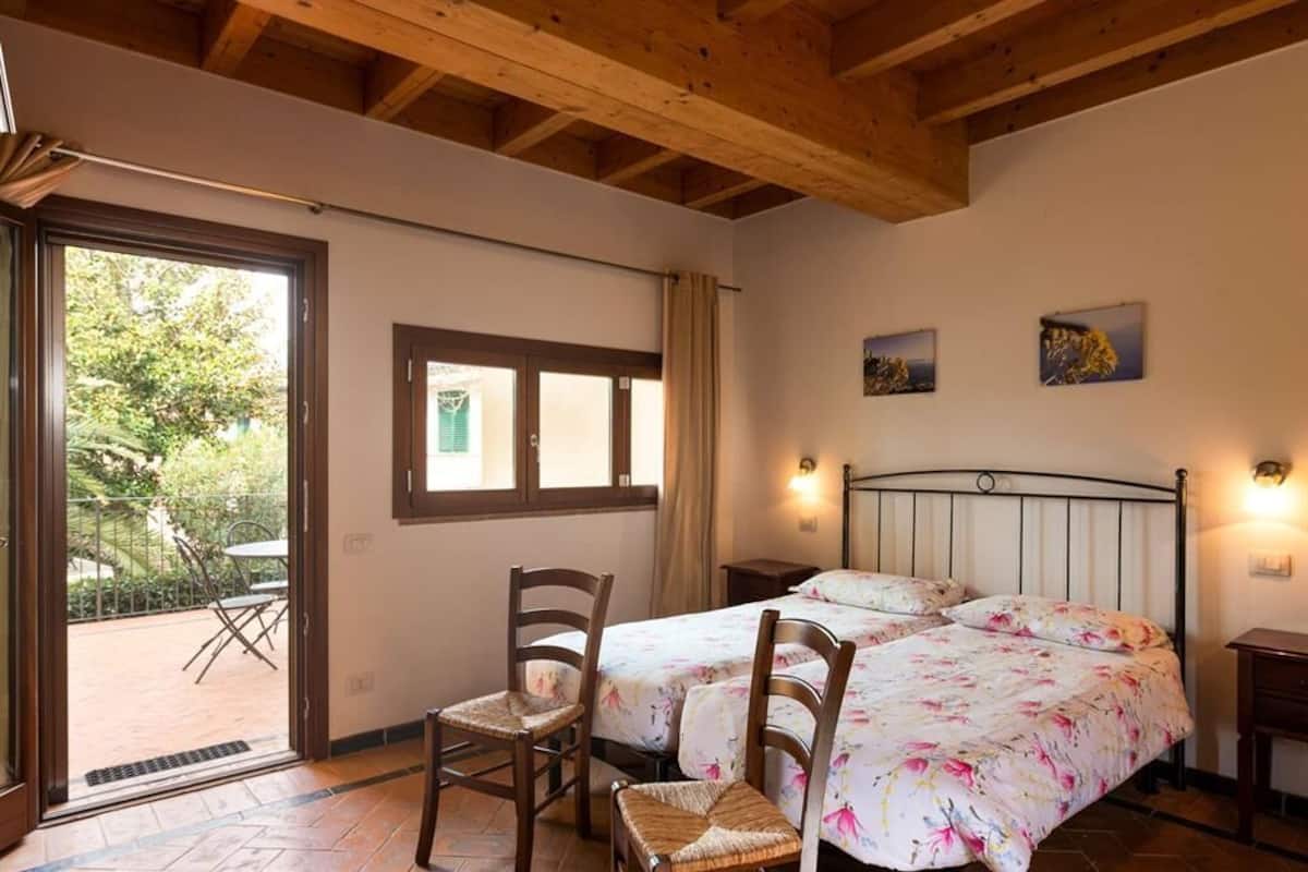 A bedroom with two beds, wooden headboard, and a window with curtains.