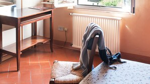Una habitación con escritorio de madera, una silla, un radiador y una ventana con puerta abierta.
