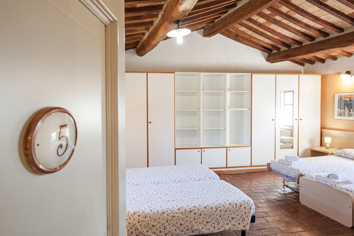 A hotel room with two beds, a large wardrobe, and a wooden ceiling.