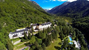 Un hotel grande con varias construcciones, rodeado de exuberante vegetación y montañas.