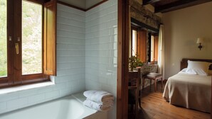 Un baño con una bañera, un banco de madera y una ventana.