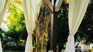 A covered outdoor dining area with a checkered tablecloth, food containers, and a variety of packaged snacks.