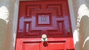 Uma porta vermelha com placa de número e fechadura.