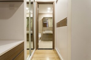 Un pasillo estrecho que conduce a un baño con inodoro, lavamanos y espejo.